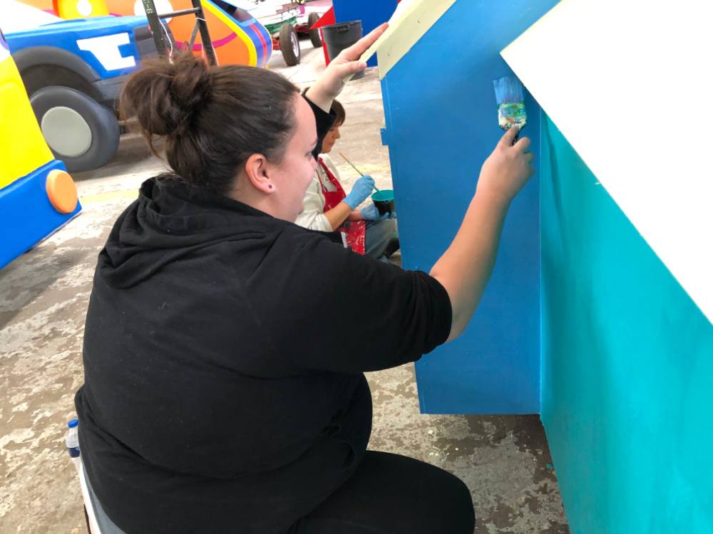 woman paints side of parade float